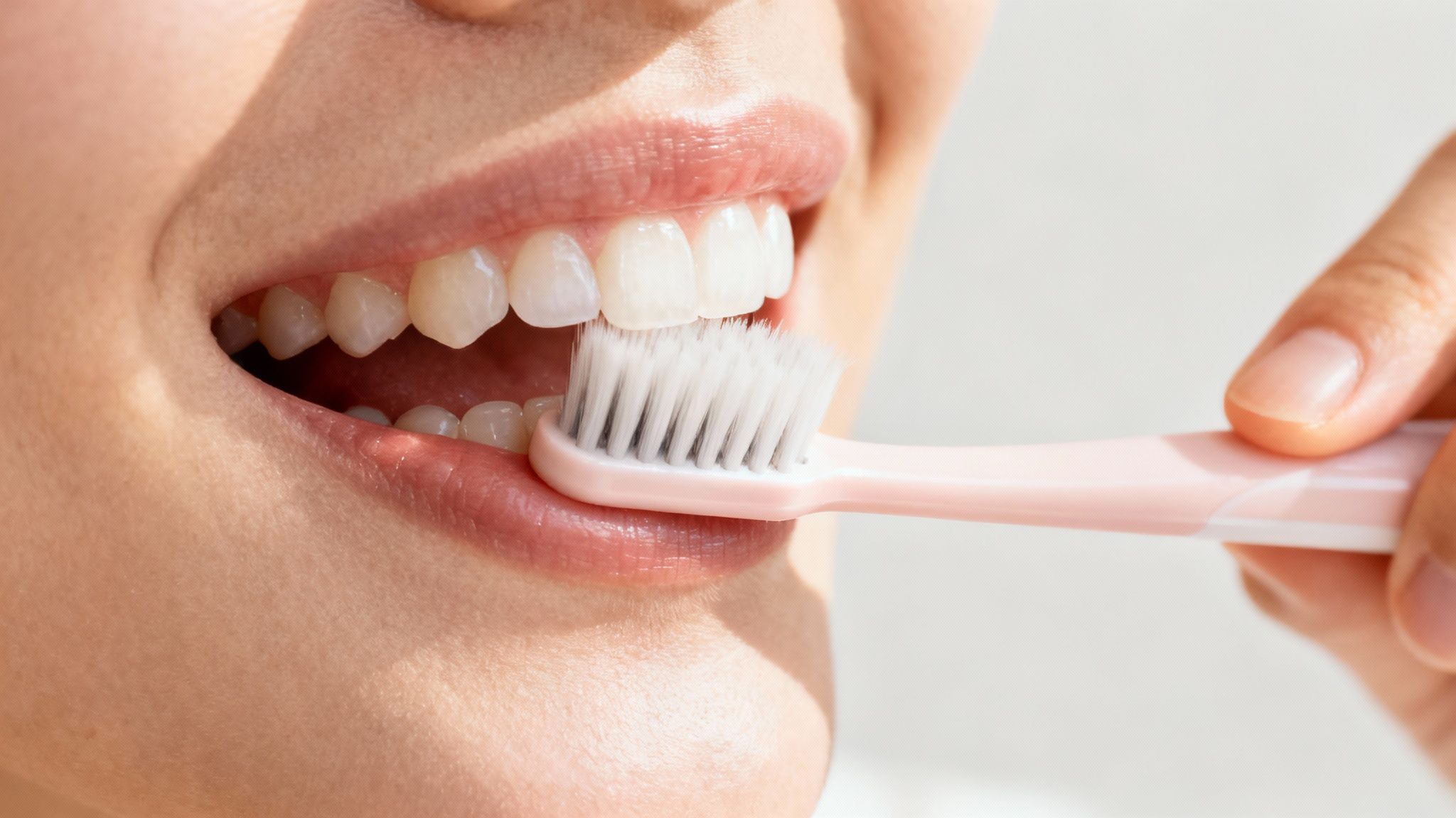 Woman brushing white teeth with soft bristle toothbrush for proper oral hygiene and gum health
