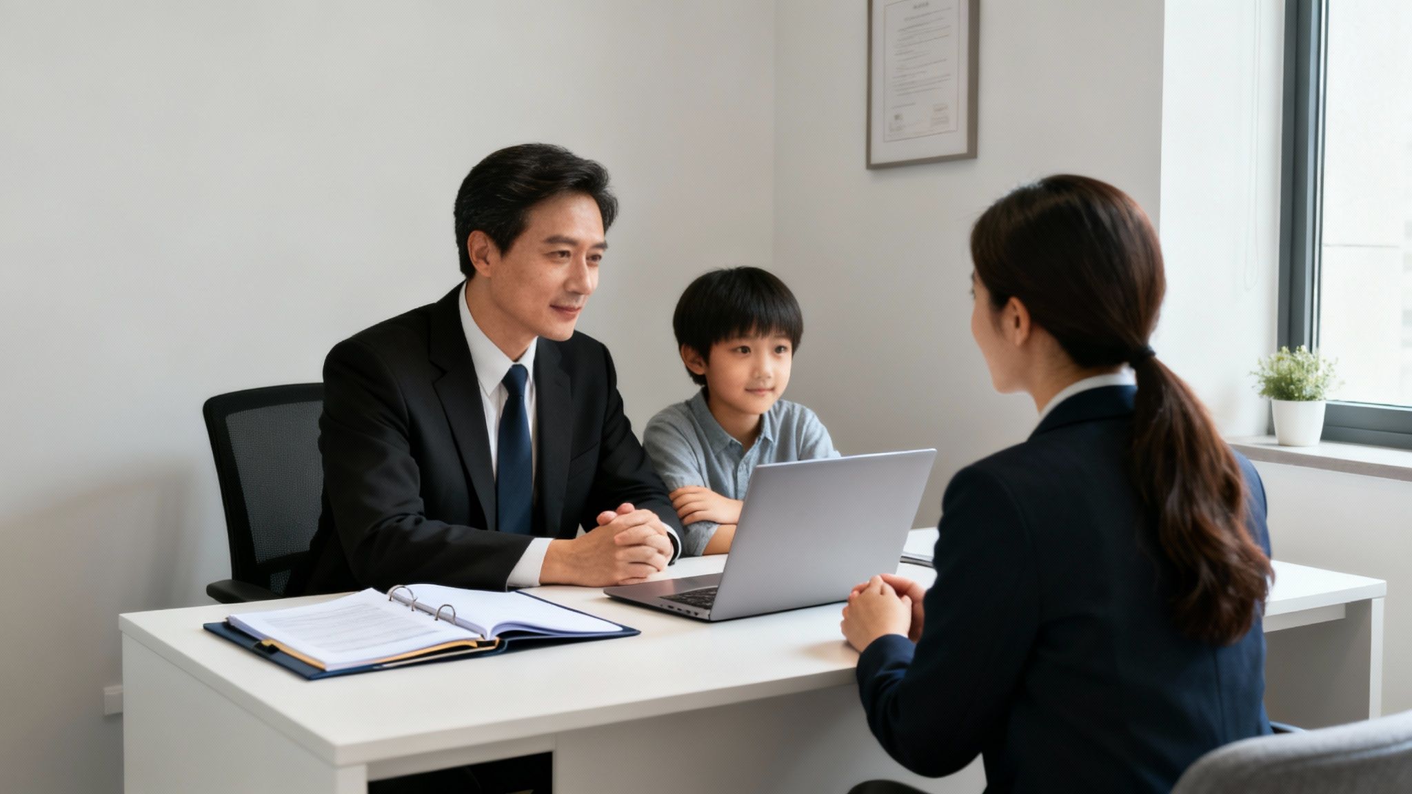 Father and child consulting with a female professional at a desk with a laptop.