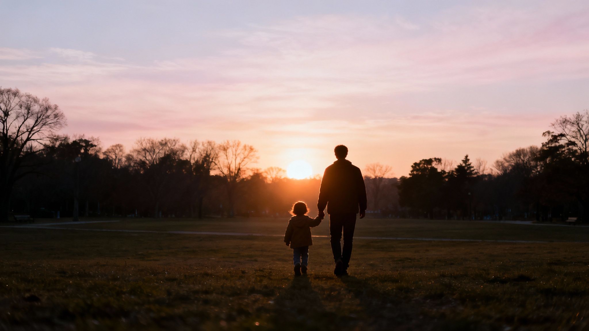 A hopeful family walking together in a sunny field.