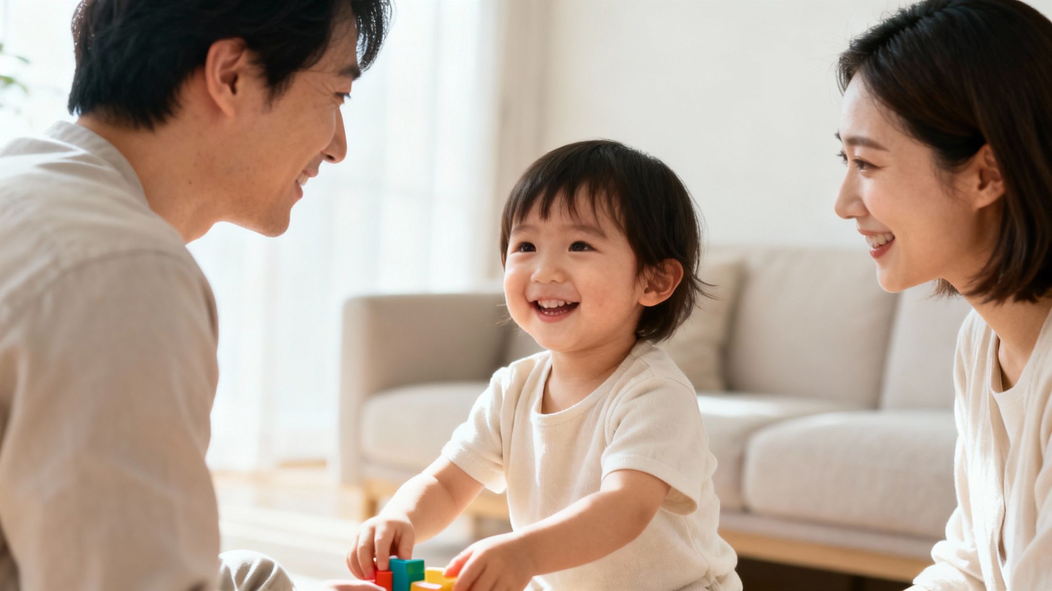 Happy family of three playing with colorful building blocks, a toddler laughing joyfully.