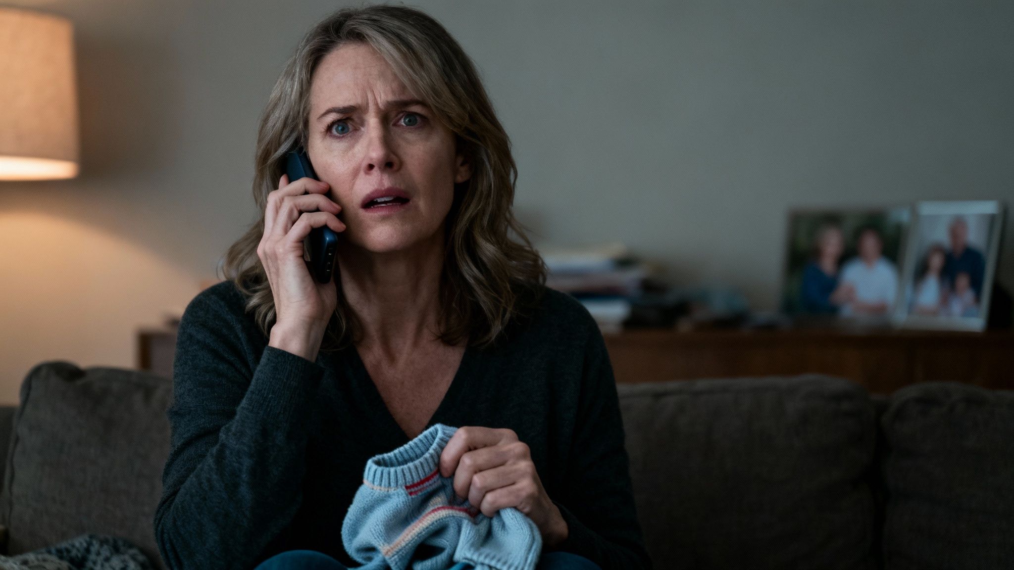 A concerned grandparent comforting a young child on a sofa.