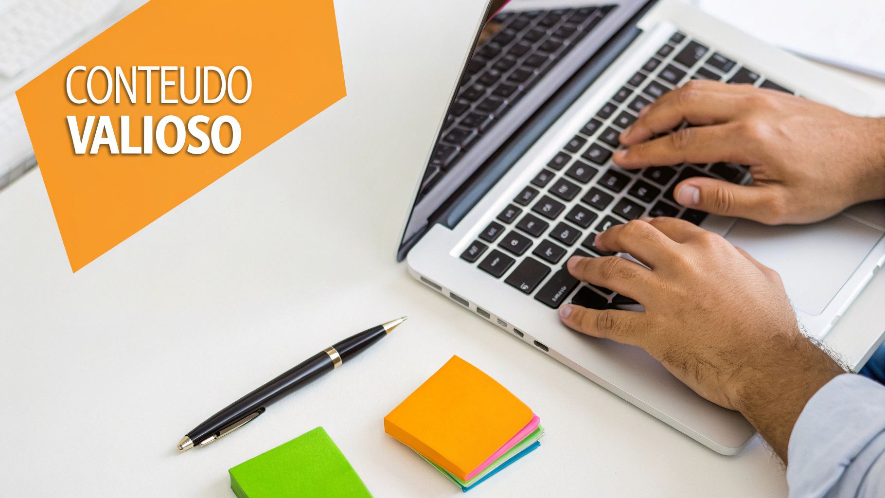 Mãos digitando em um laptop, caneta e notas adesivas em uma mesa branca com banner laranja 'Conteúdo Valioso'.