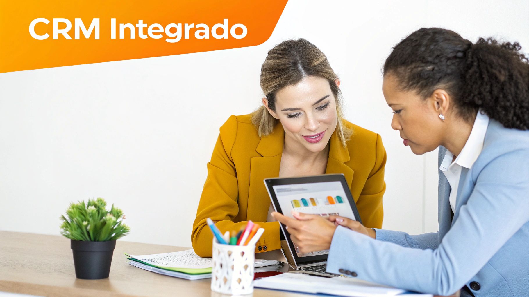 Duas mulheres de negócios colaboram em um tablet, mostrando gráficos, com a frase "CRM Integrado" destacada.