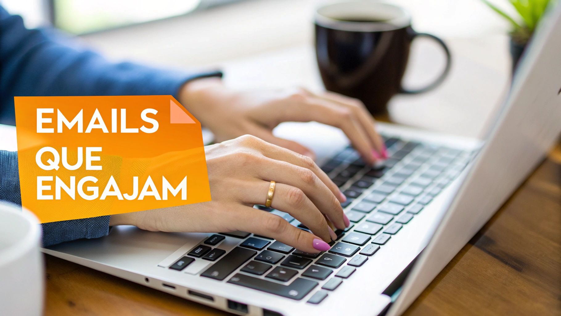 Mãos digitando em um laptop com unhas rosa, anel dourado e texto 'EMAILS QUE ENGAGAM' em destaque, ao lado de uma xícara de café.