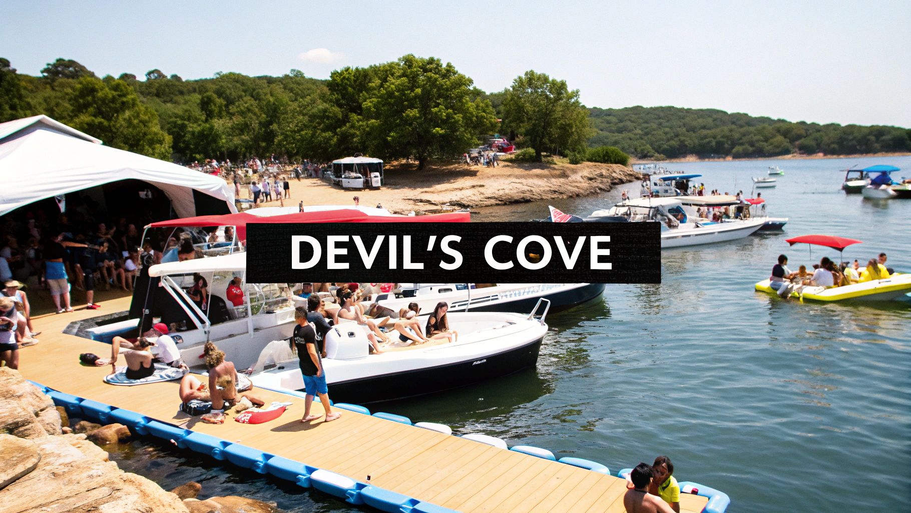 Many people and boats gather at Devil's Cove on a sunny day, with a large tent on shore.