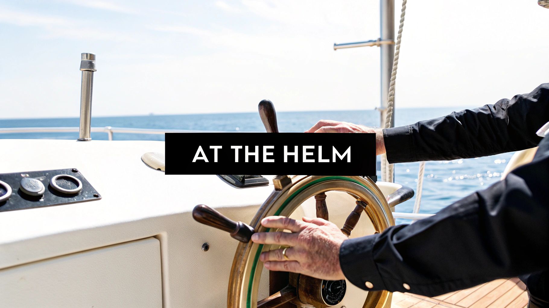 A person's hands steering a wooden boat helm with the sparkling blue ocean in the background.