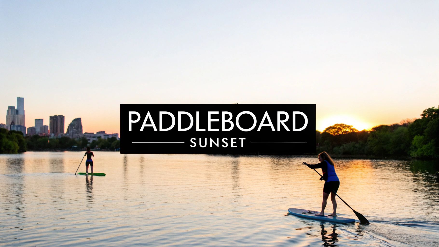 Two people paddleboarding on a serene lake at sunset with a city skyline in the background.