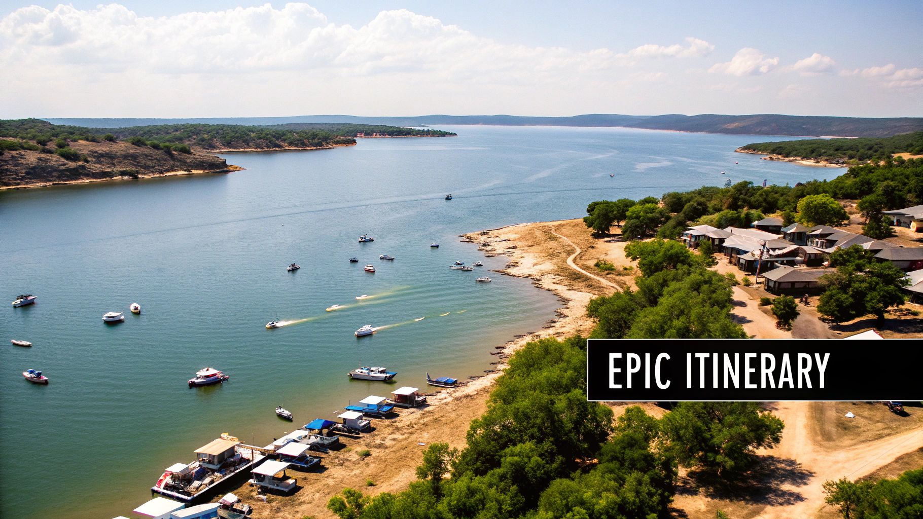 Aerial view of a wide lake with many boats, surrounded by wooded hills and lakeside buildings on a sunny day.