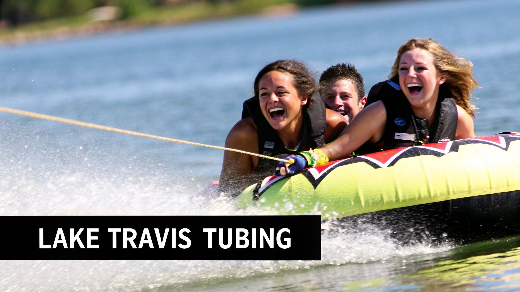 Young adults in life vests happily tubing on a tube pulled by boat, creating spray on Lake Travis.