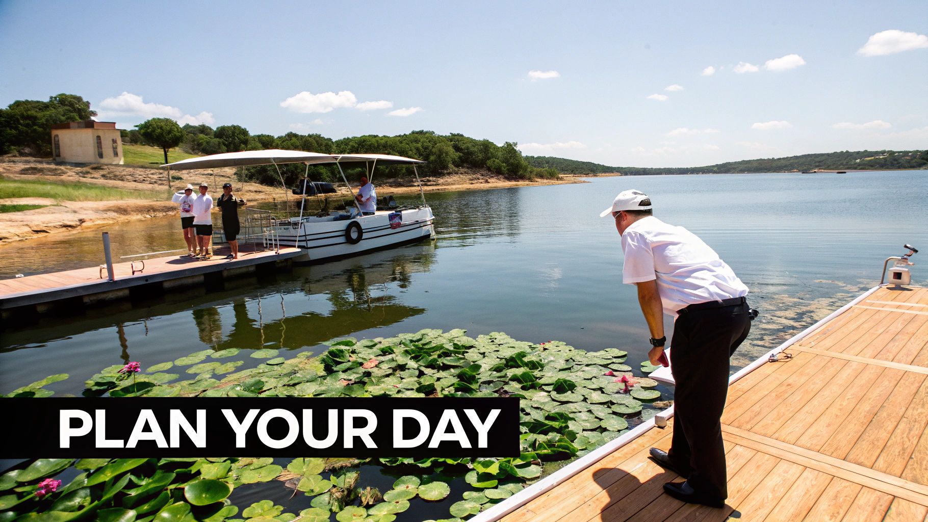 People on docks next to a lake with a pontoon boat and water lilies on a sunny day.