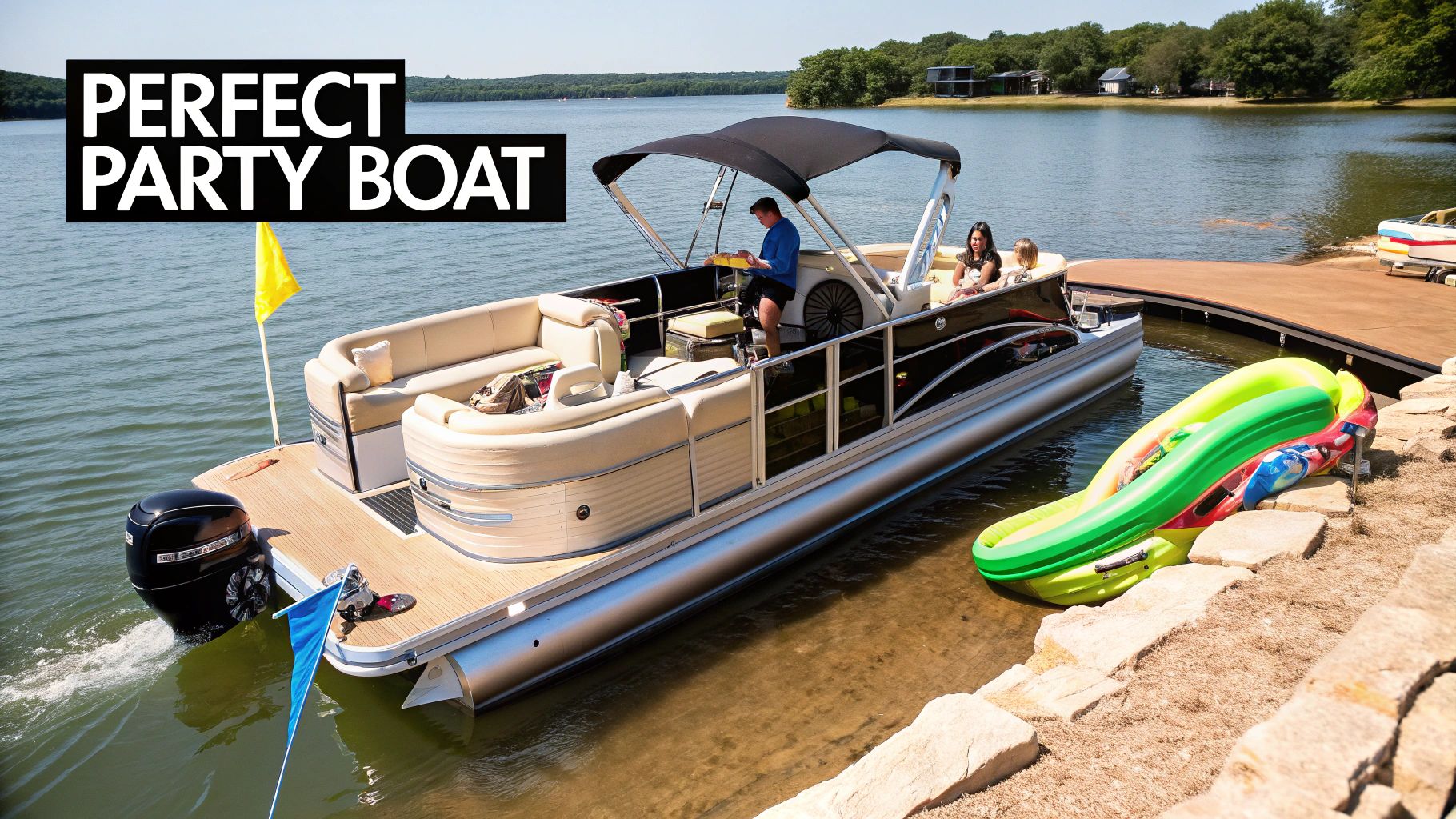 A pontoon party boat with people on board is docked on a sunny lake next to an inflatable slide.