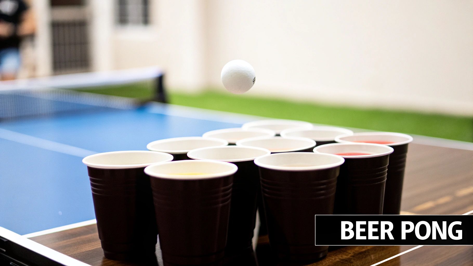 A close-up shot of a beer pong setup with brown cups on a wooden table, a ping-pong ball in mid-air above them.