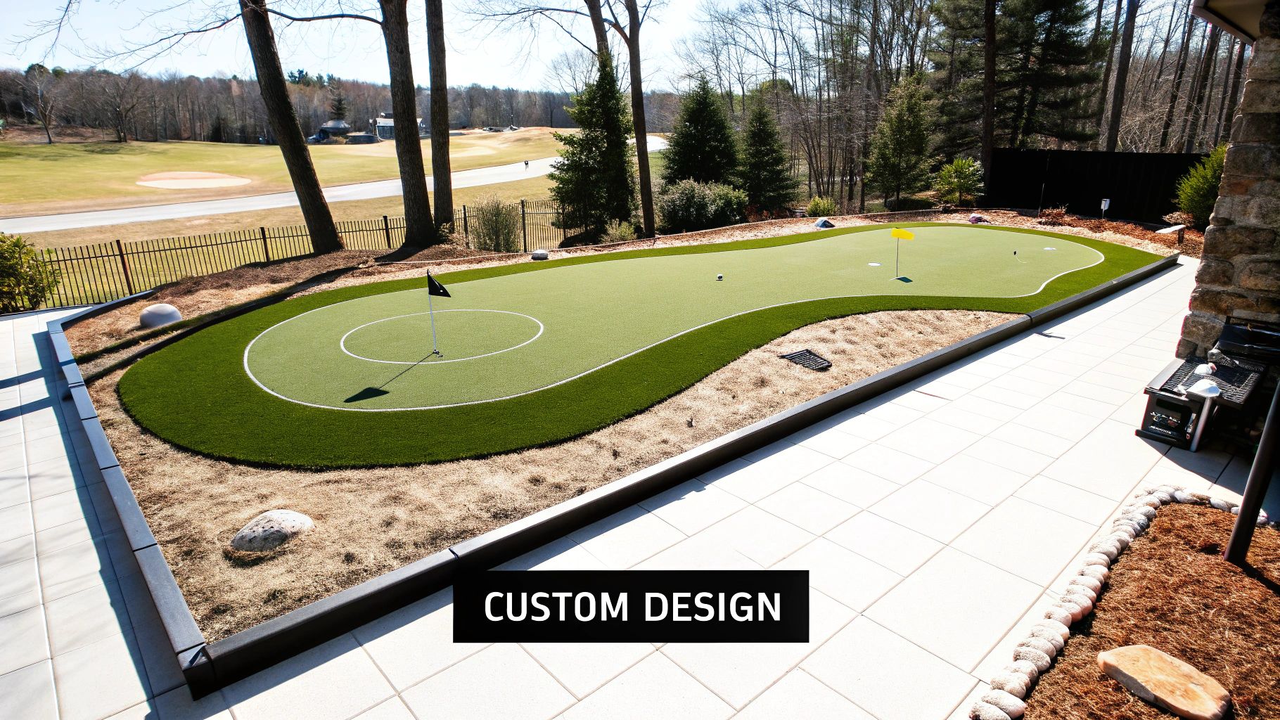 A custom-designed artificial turf putting green in a beautiful backyard, overlooking a golf course, with a paved patio.