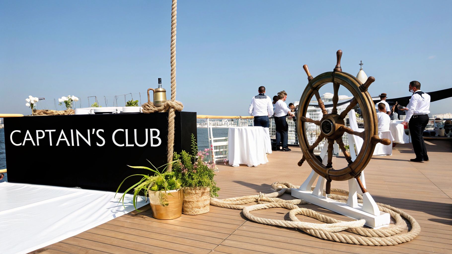 A Captain's Club event on a deck with a large ship's wheel, staff, and nautical decor.