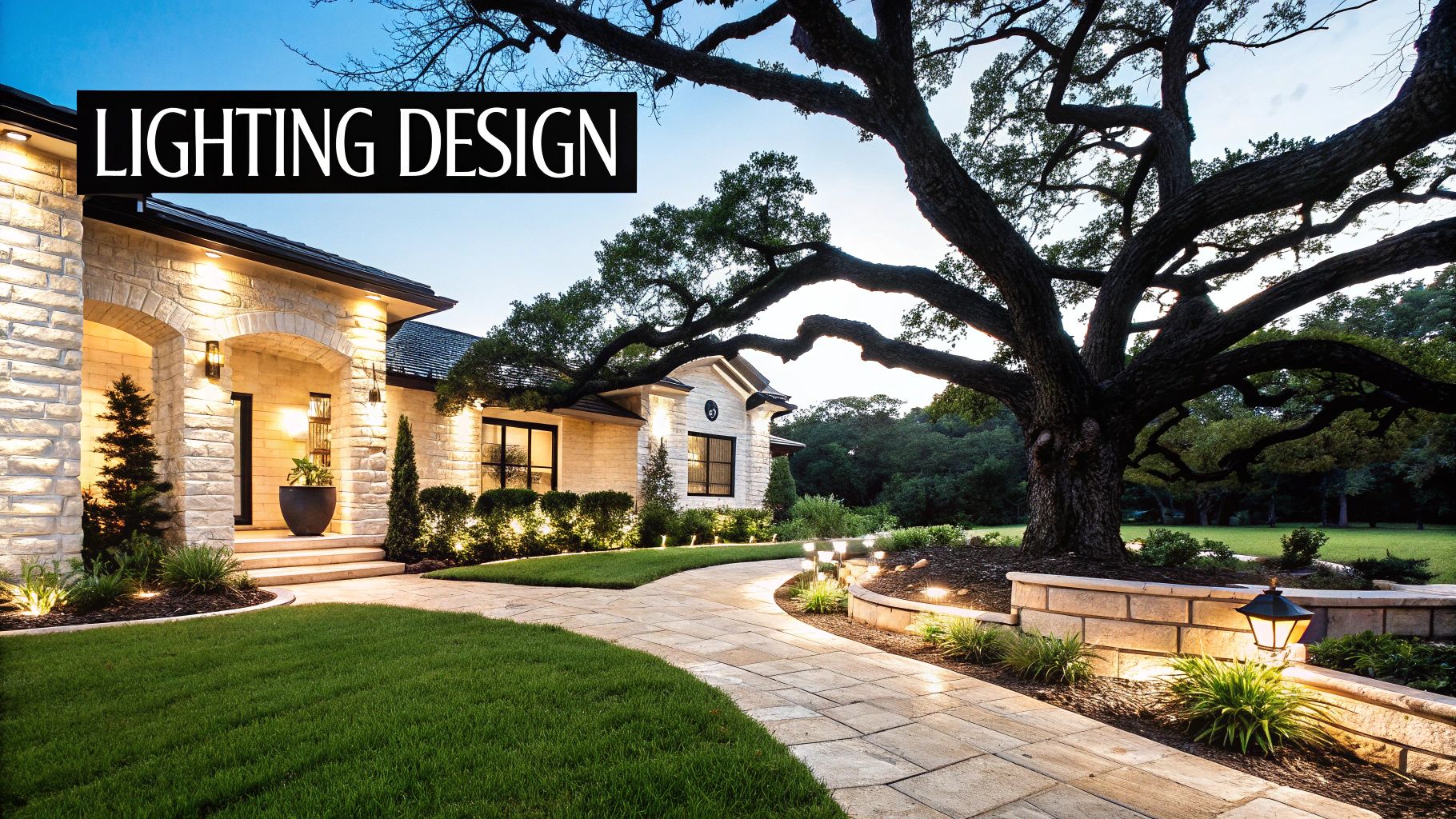 Exterior view of a beautifully lit house, paved walkway, and landscaped garden with a large tree at dusk.