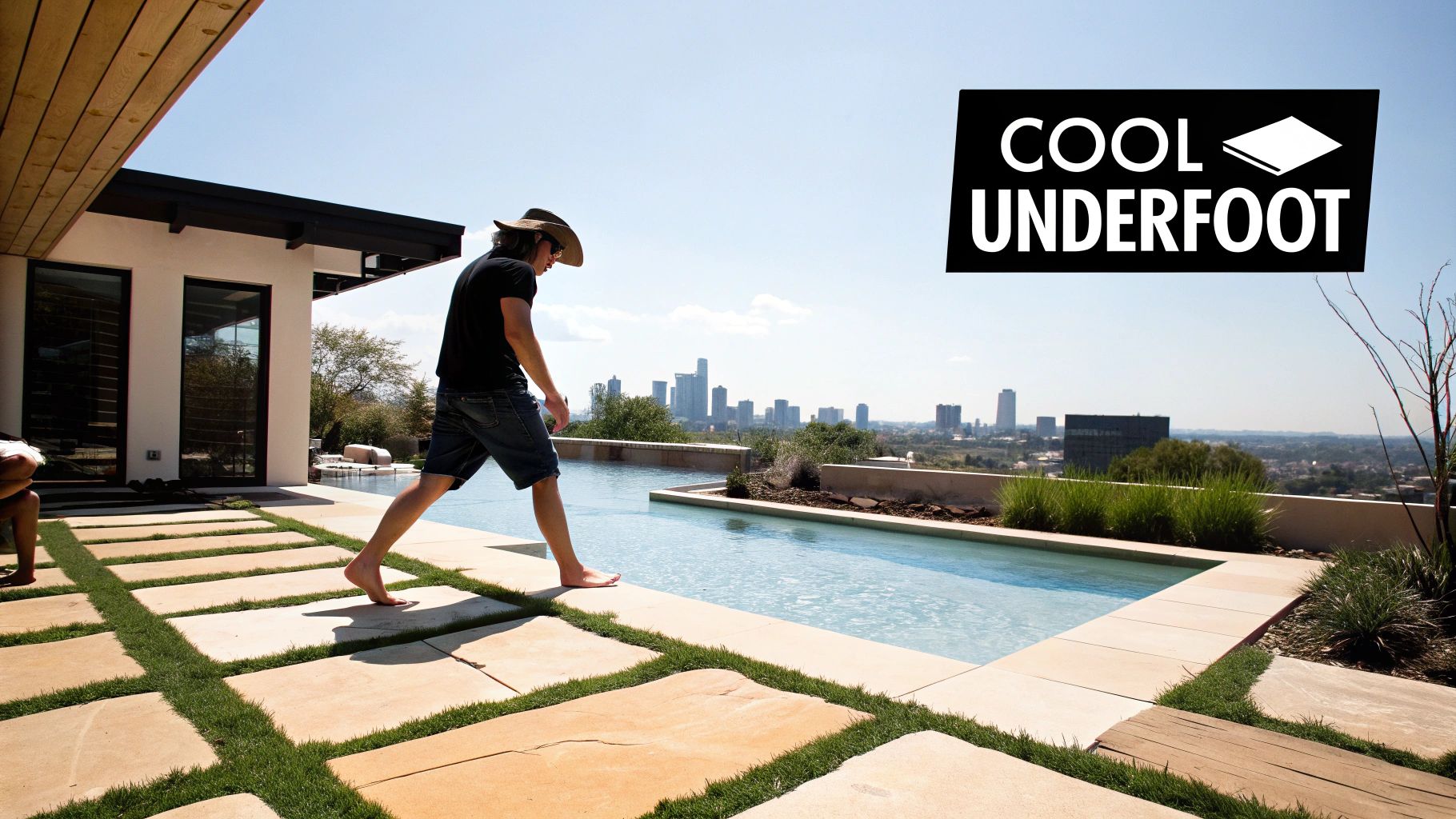 A person walks barefoot on light-colored pavers next to a swimming pool with a city view.