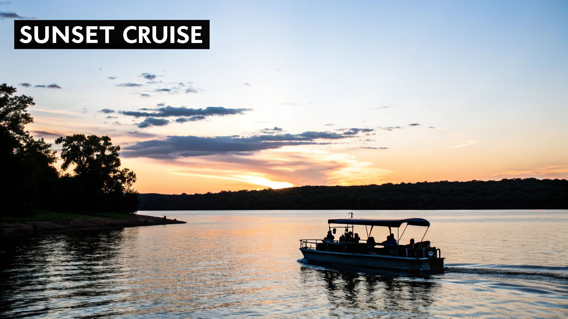A scenic view of a boat filled with people cruising on a lake during a beautiful sunset.