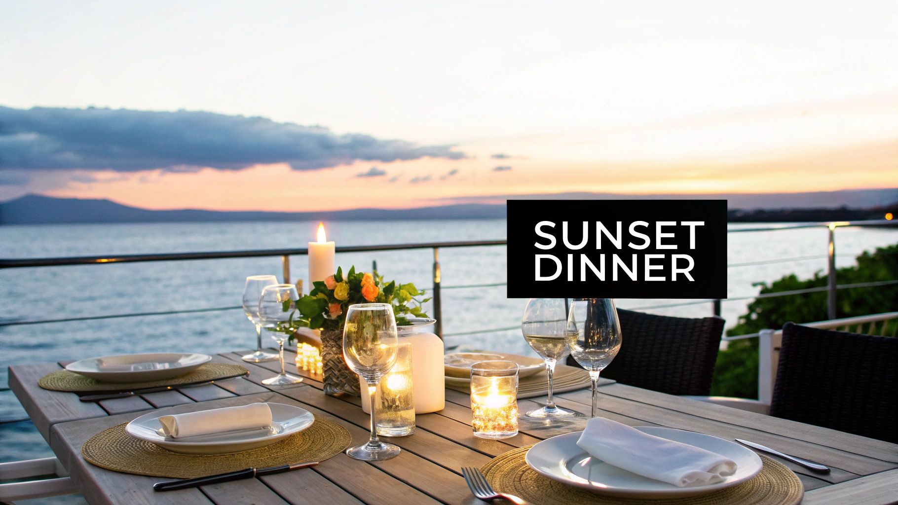 A romantic sunset dinner table setting by the sea with candles and wine glasses.