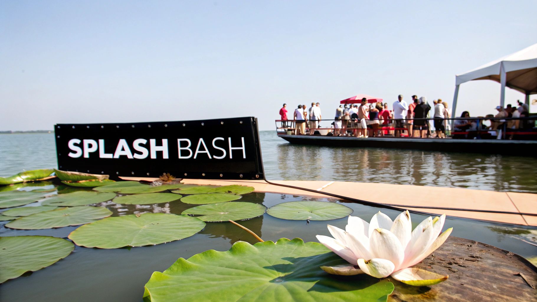 A "Splash Bash" event on a lake with a boat, people, and beautiful water lilies.