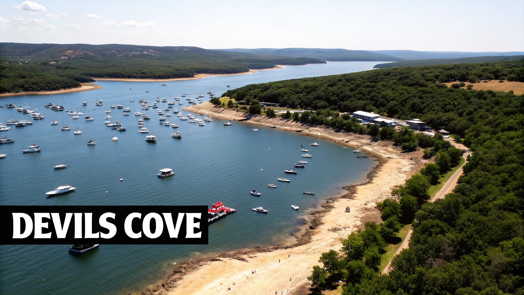 Aerial view of Devil's Cove on Lake Travis, filled with many boats, surrounded by green hills.
