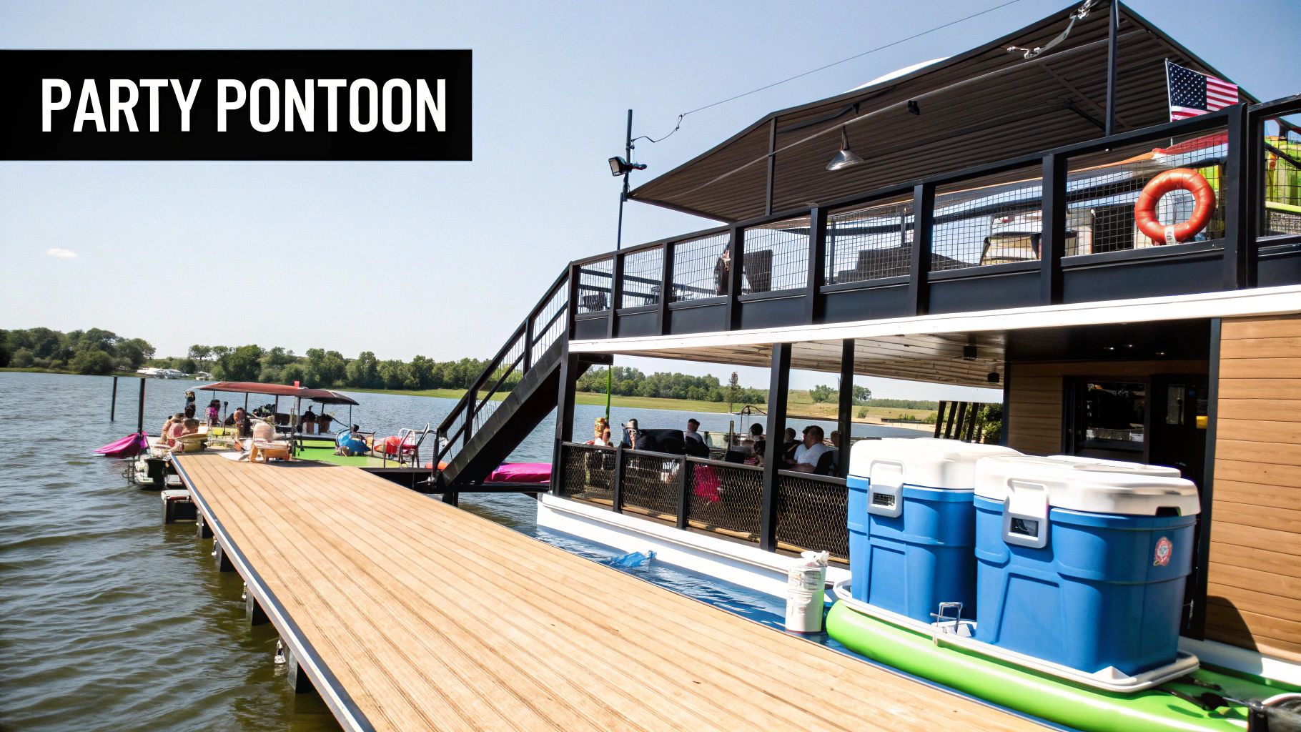 A lively two-story party pontoon boat docked on a sunny lake with people enjoying the deck.