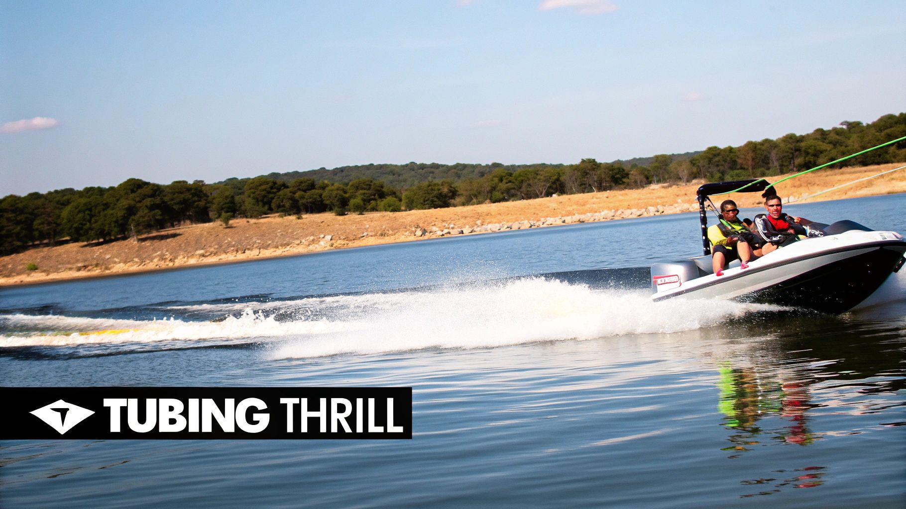 Two people on a powerboat speed across a sunny lake, with a tow rope for water tubing.
