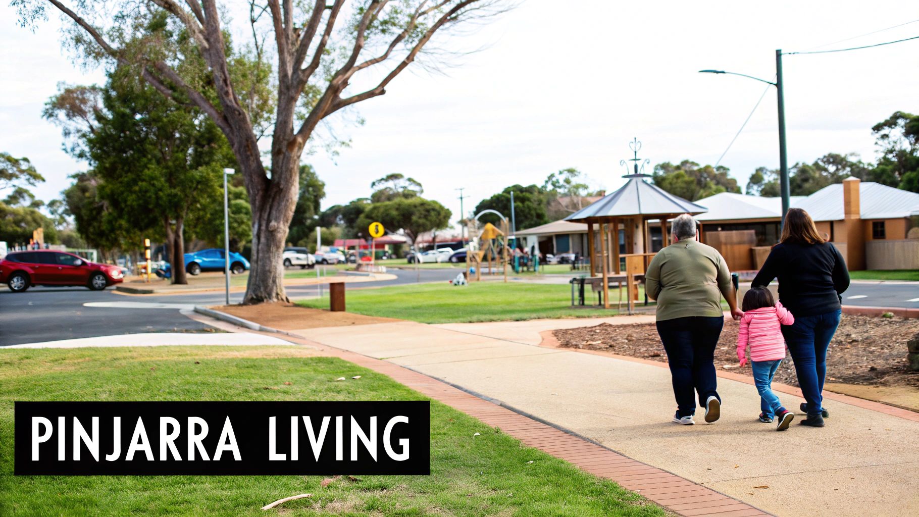 Two adults and a child walk through a park in Pinjarra, with a playground and homes in the background.