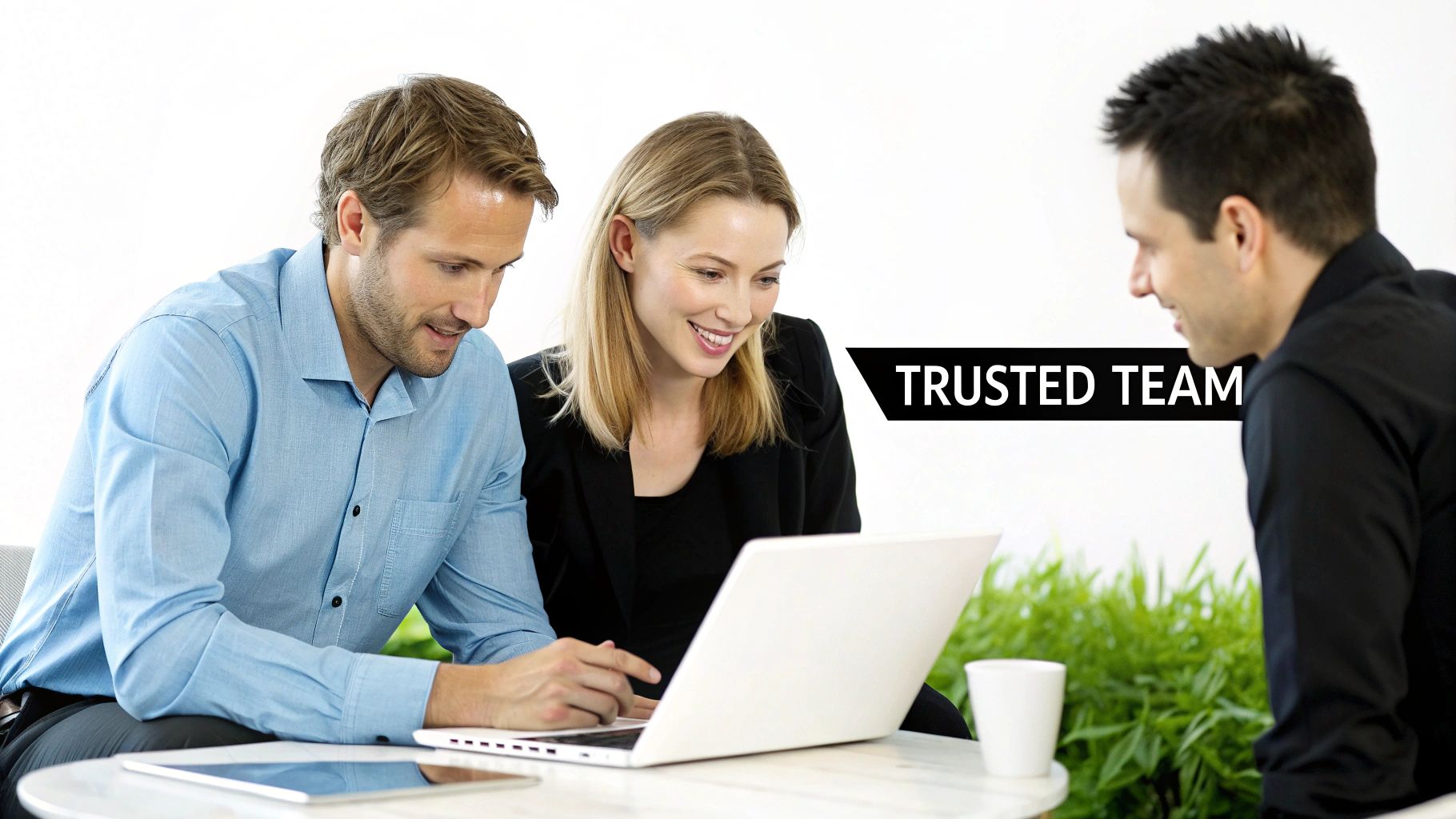 Three business professionals collaborating around a laptop in a bright modern office, embodying a trusted team.
