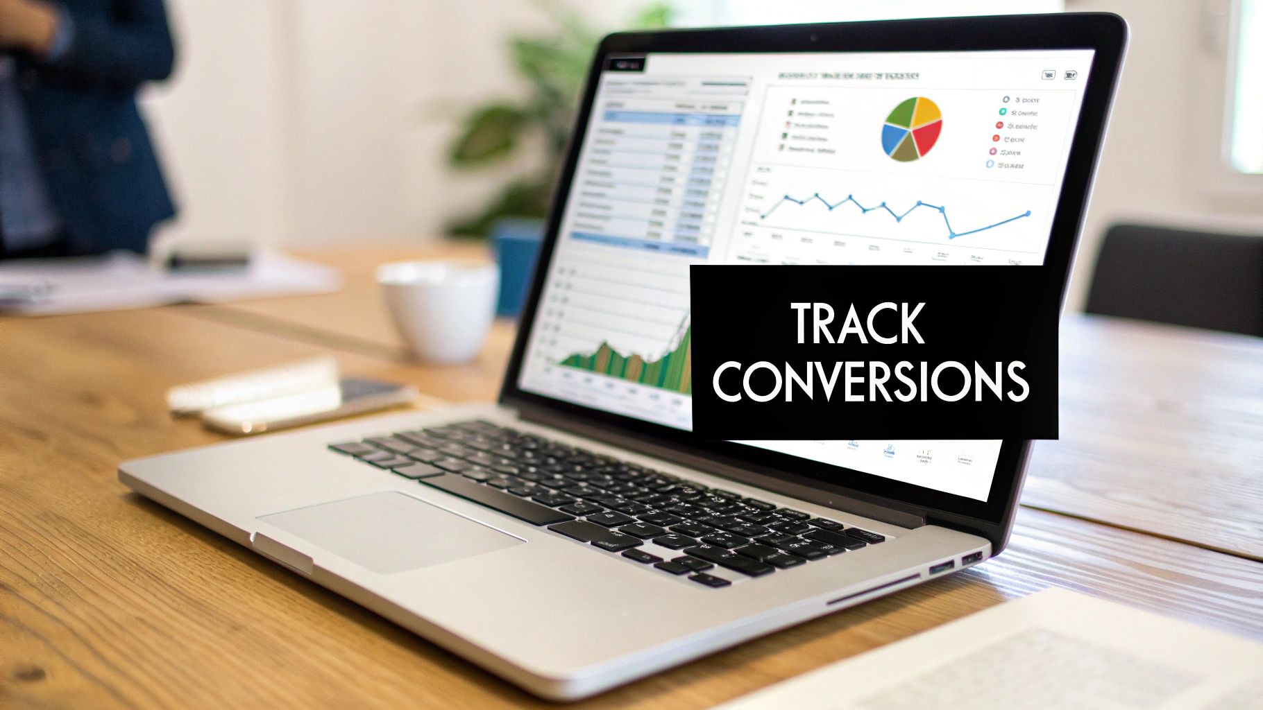 Laptop on a wooden desk displaying business analytics with a 'TRACK CONVERSIONS' text overlay.