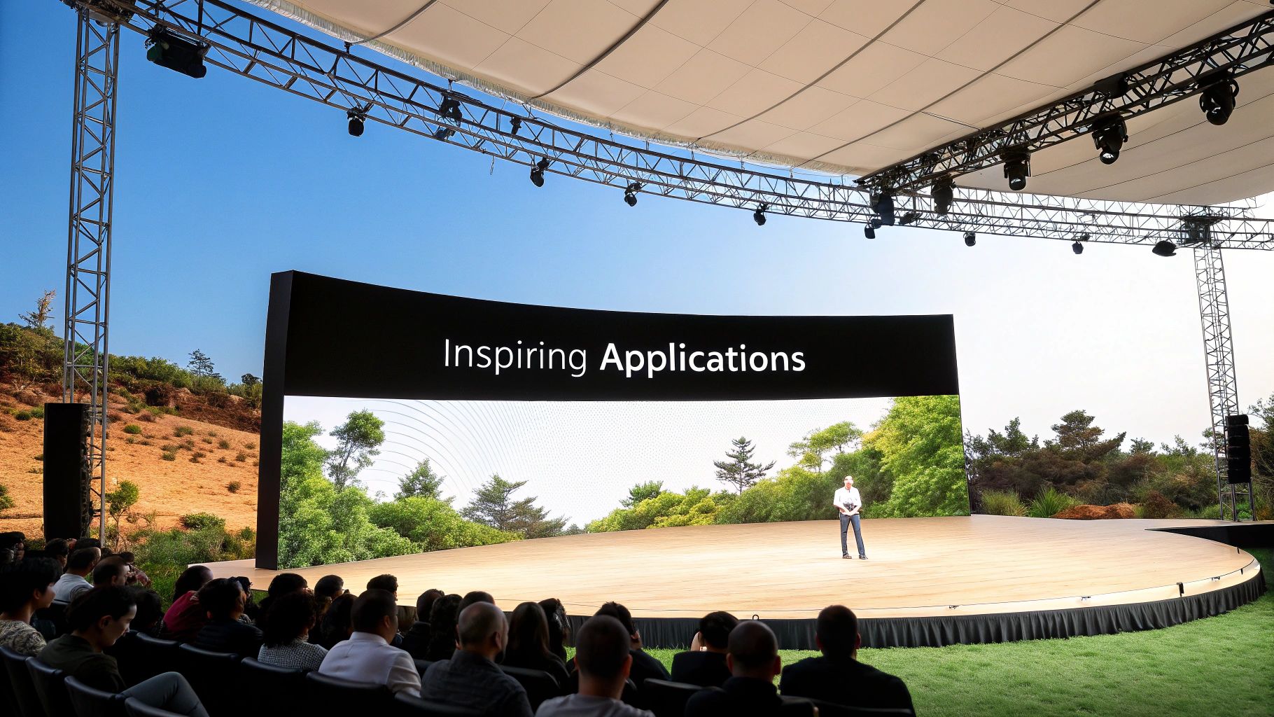 Flexible LED Panel A Guide to Curved Digital Displays 3 A speaker stands on a large outdoor stage with a curved LED screen displaying "Inspiring Applications" to an audience.