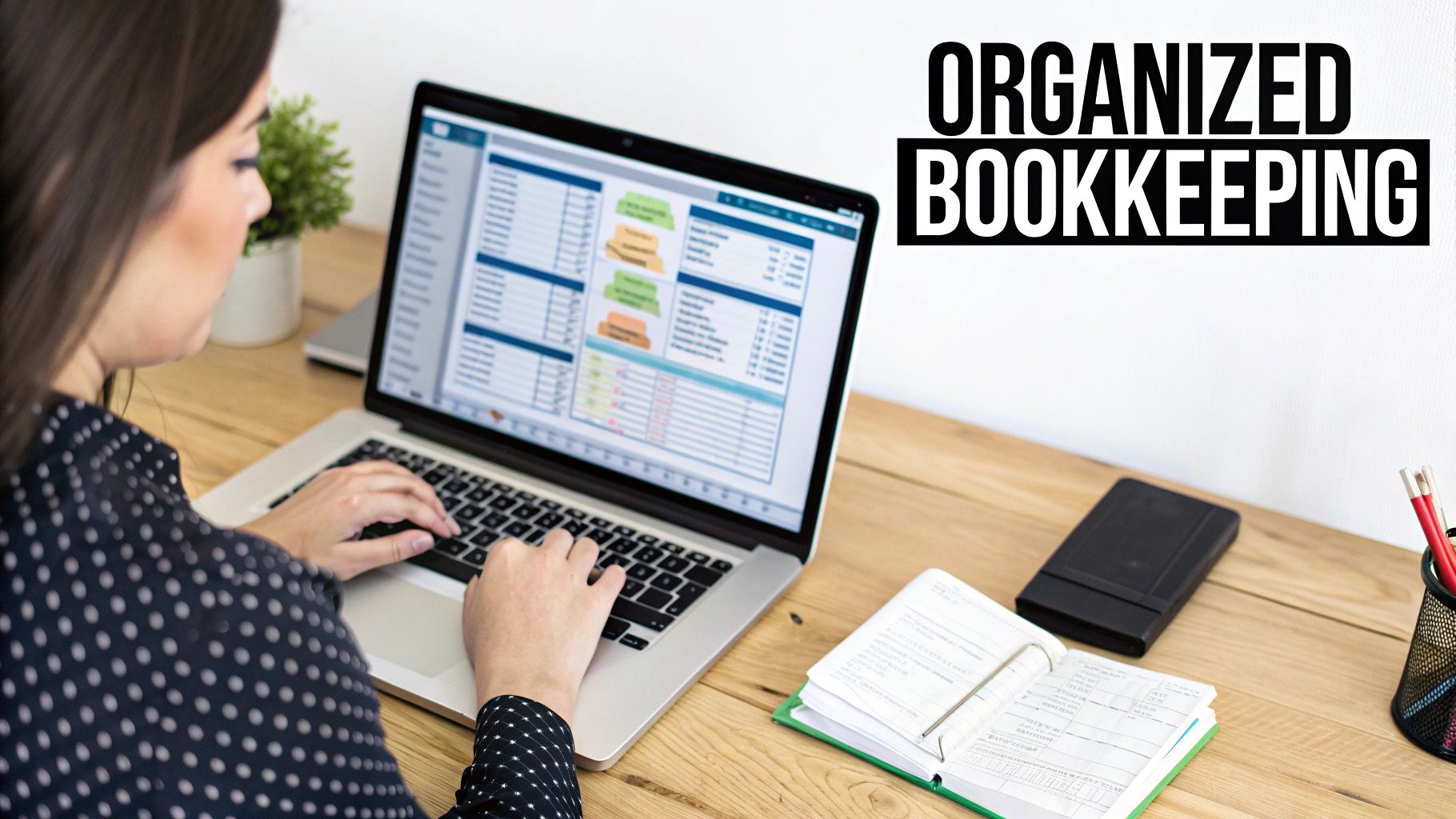 A person works on a laptop with financial data, alongside an open ledger, demonstrating organized bookkeeping.