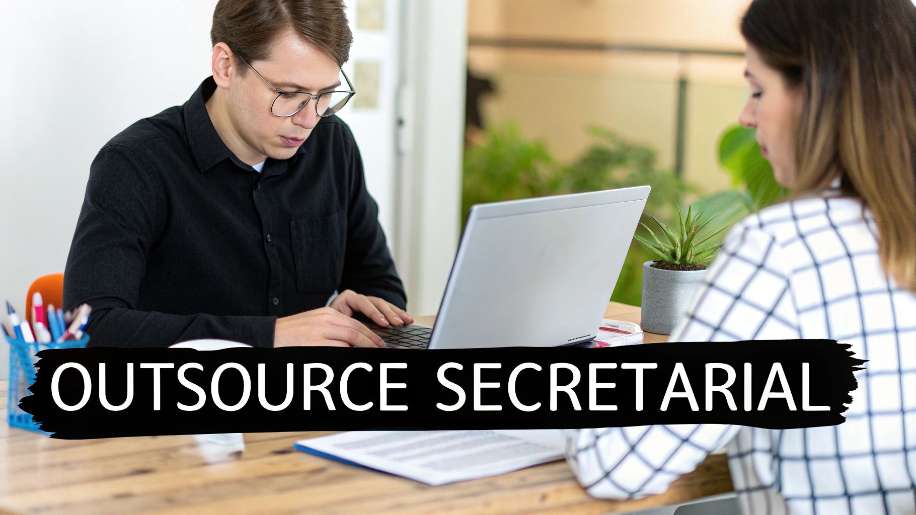 A professional works on a laptop at a clean, modern desk with a plant, representing focus and efficiency.