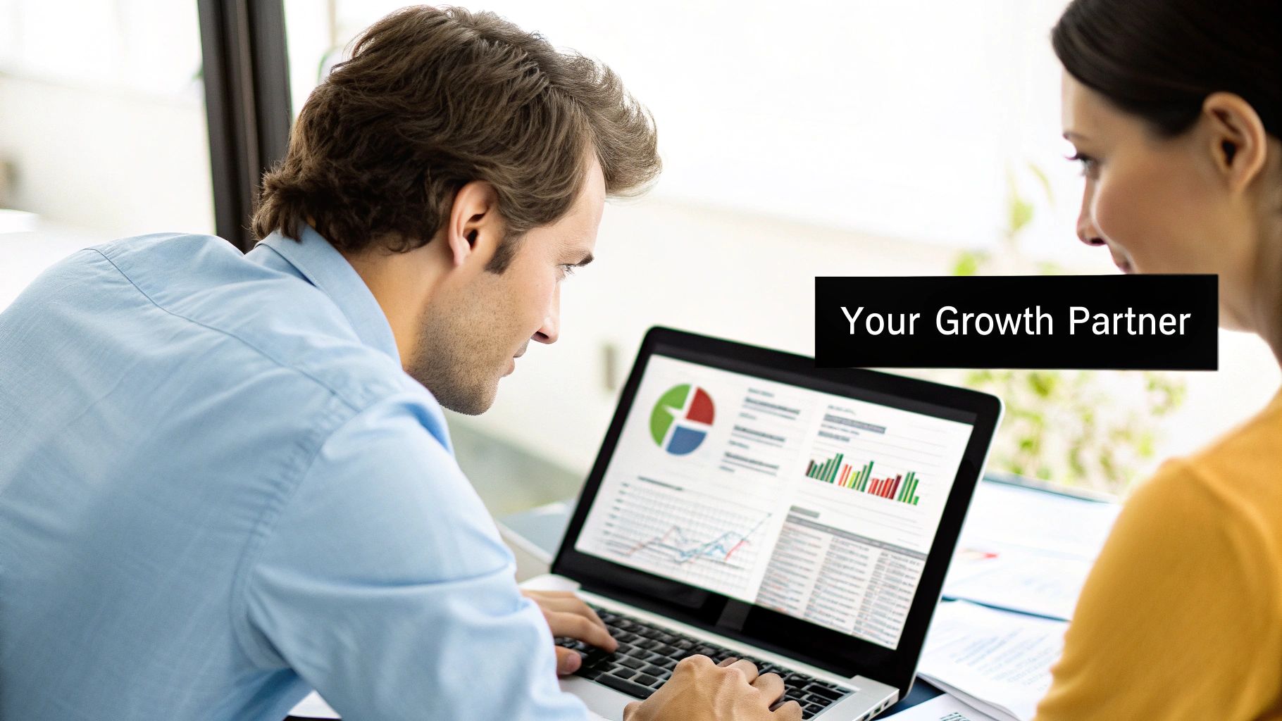 Two business professionals collaborating, looking at data analytics on a laptop screen with charts and graphs.