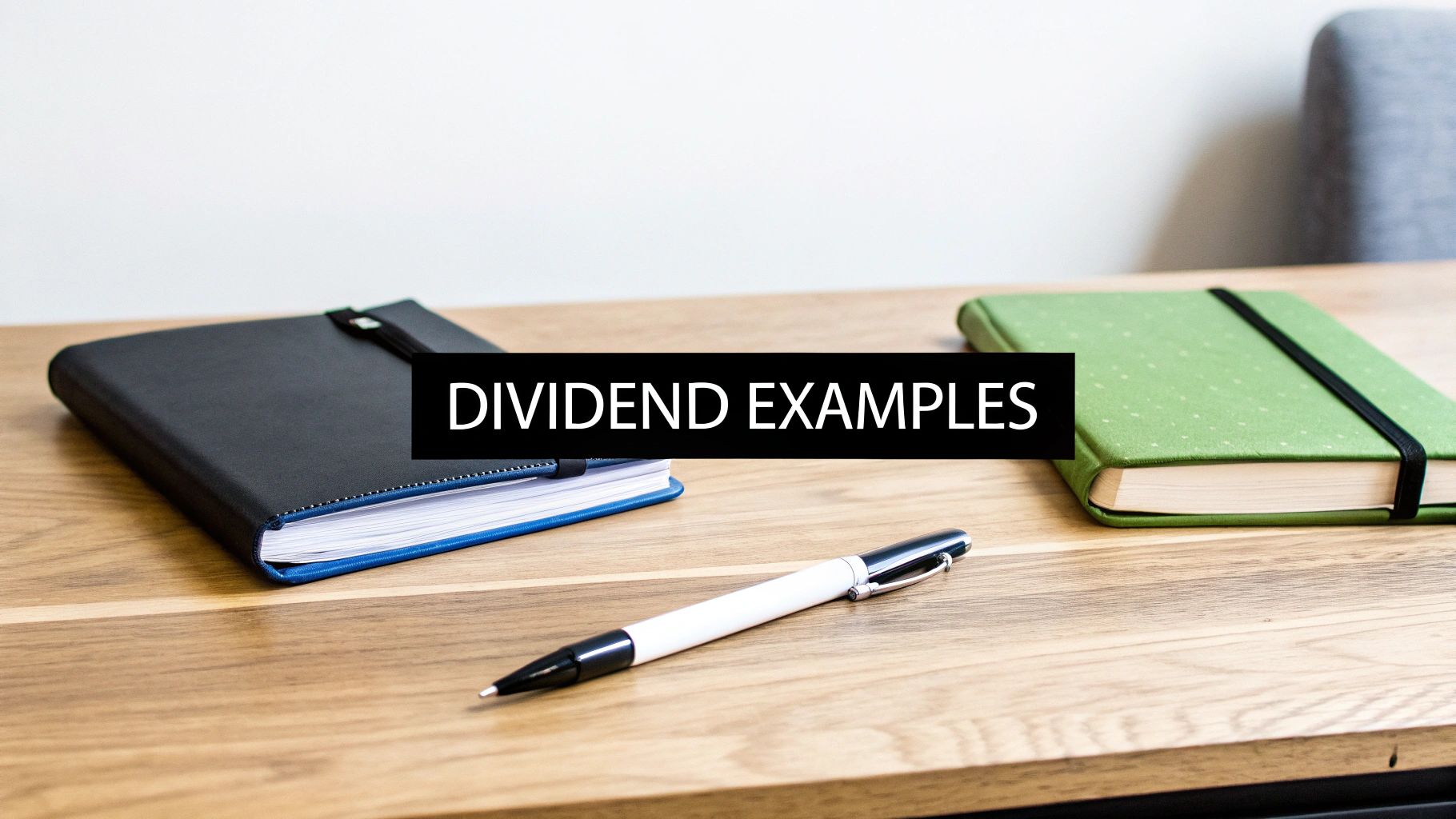 A wooden desk with two notebooks, a pen, and text overlay 'DIVIDEND EXAMPLES'.