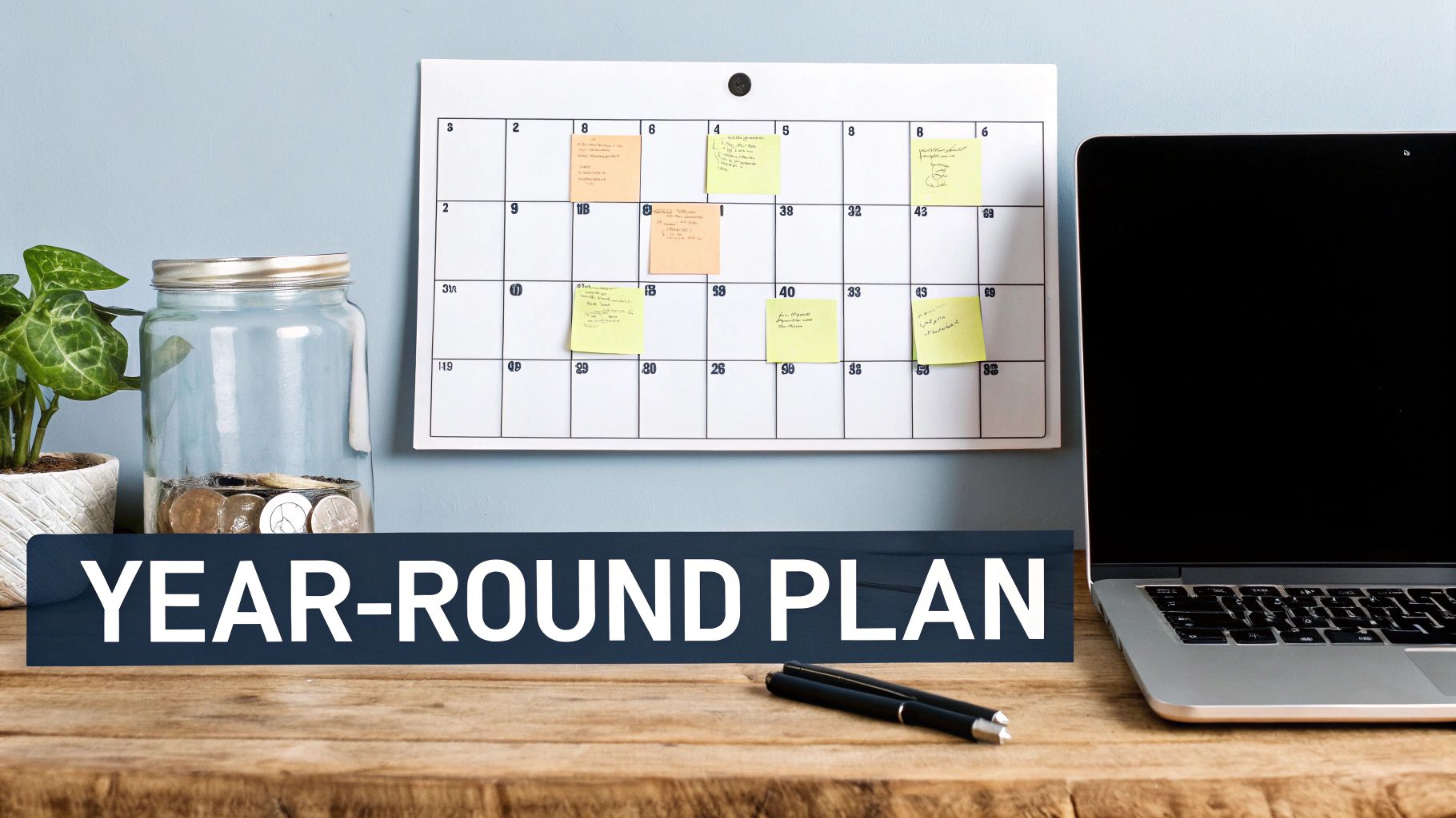 A desk with a laptop, calendar, money jar, and a 'YEAR-ROUND PLAN' banner.