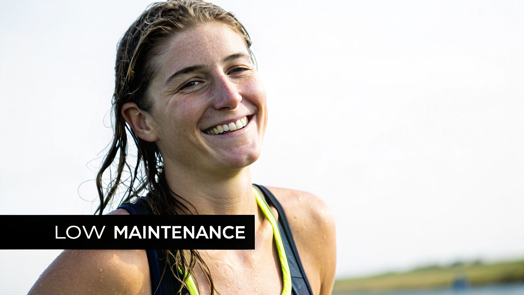 A beautiful woman with wet, natural hair smiling happily, embracing a low-maintenance look.