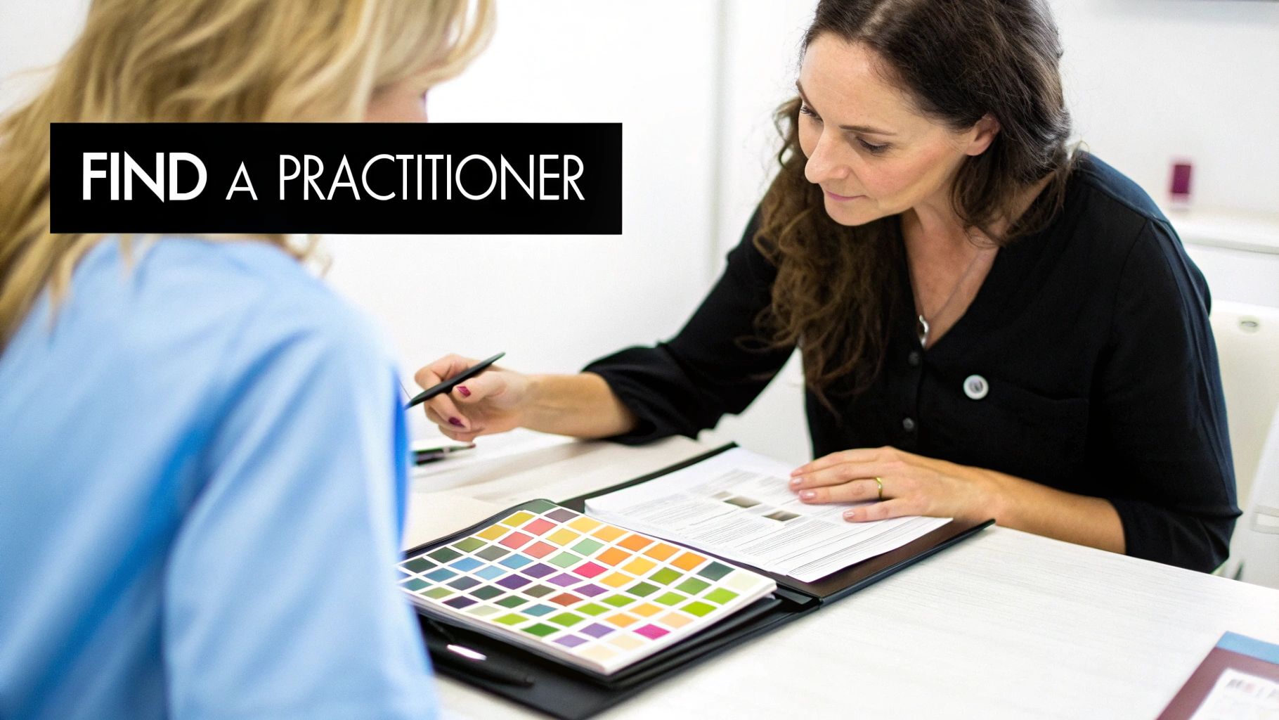 Two women discussing, one pointing at documents and color swatches on a table. Text: FIND A PRACTITIONER.