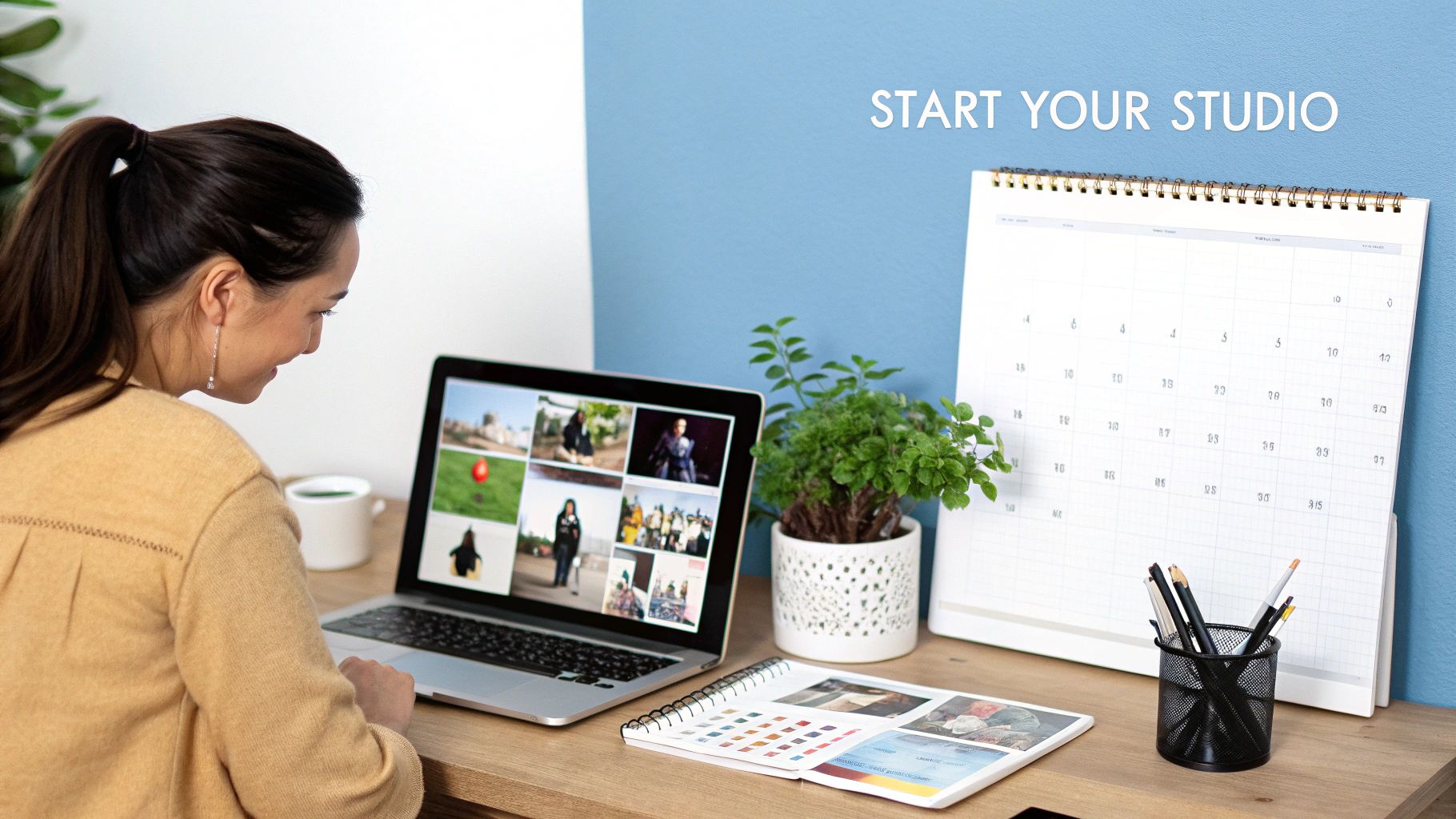Young woman reviewing photos on a laptop at a creative studio desk with a calendar.