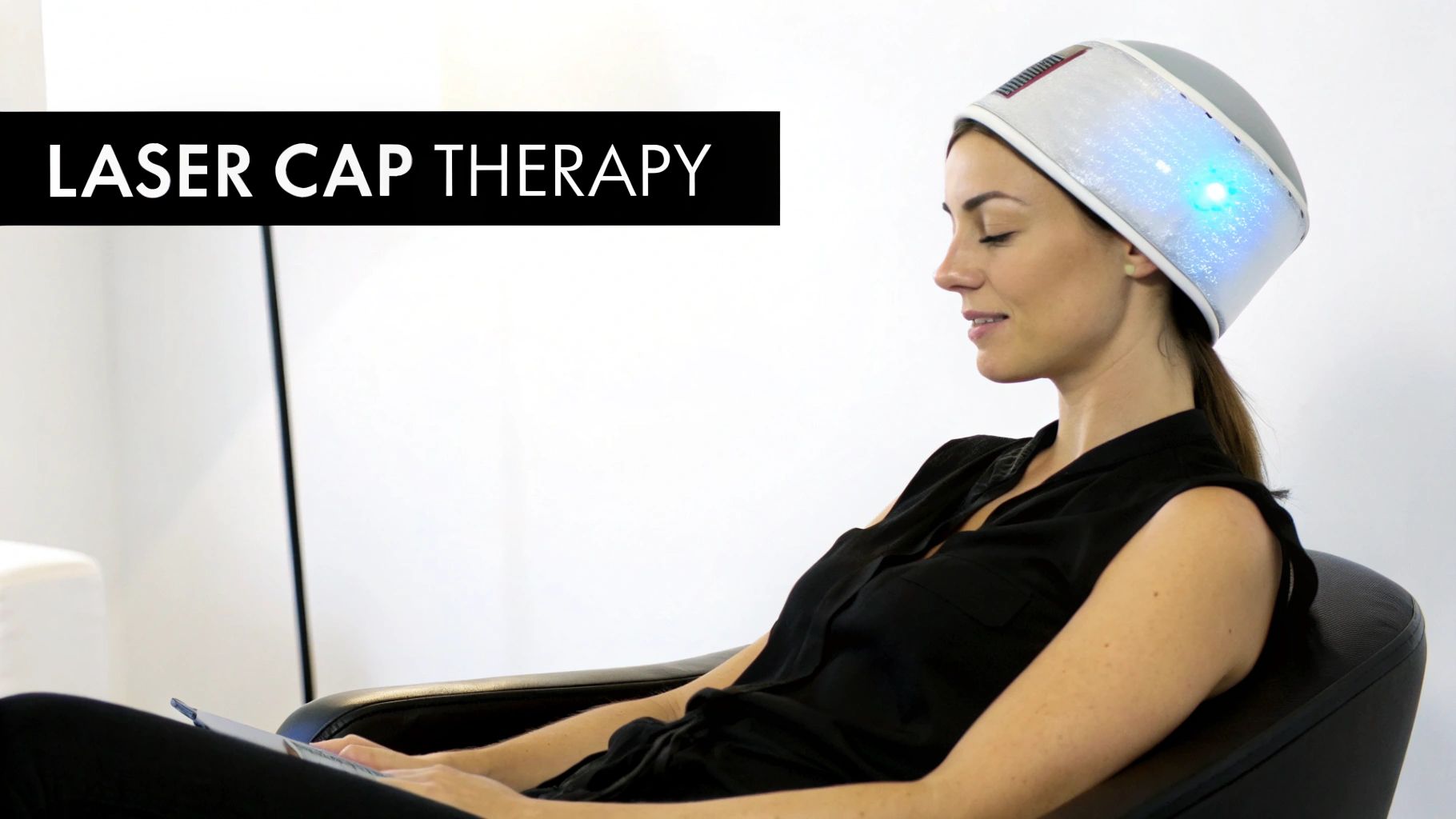 Side profile of a woman using a light-up laser cap for hair growth therapy.