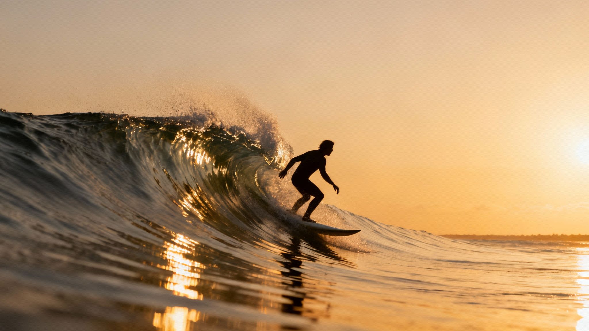 A silhouette of a surfer riding a powerful ocean wave at golden hour.