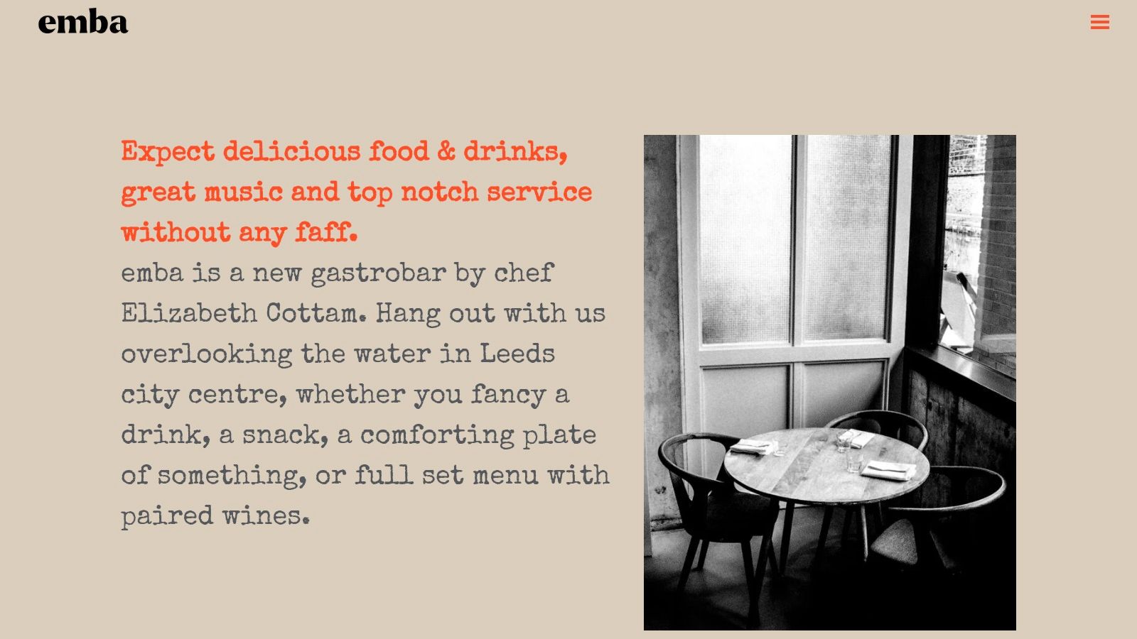 The stylish interior of emba, with warm lighting, modern furniture, and a view of the bar area.