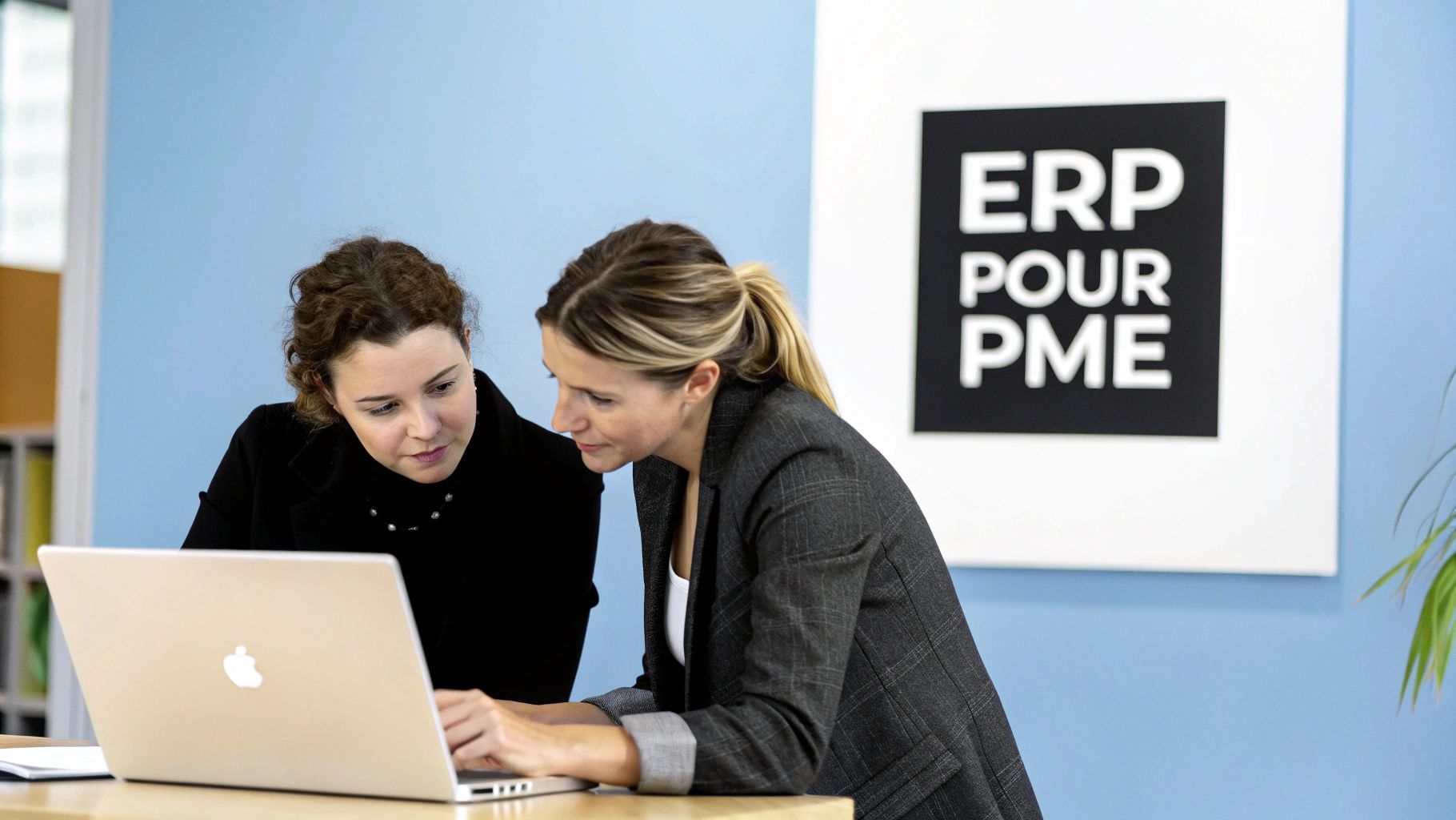 Deux femmes professionnelles collaborent devant un ordinateur portable dans un bureau, avec un panneau "ERP POUR PME".