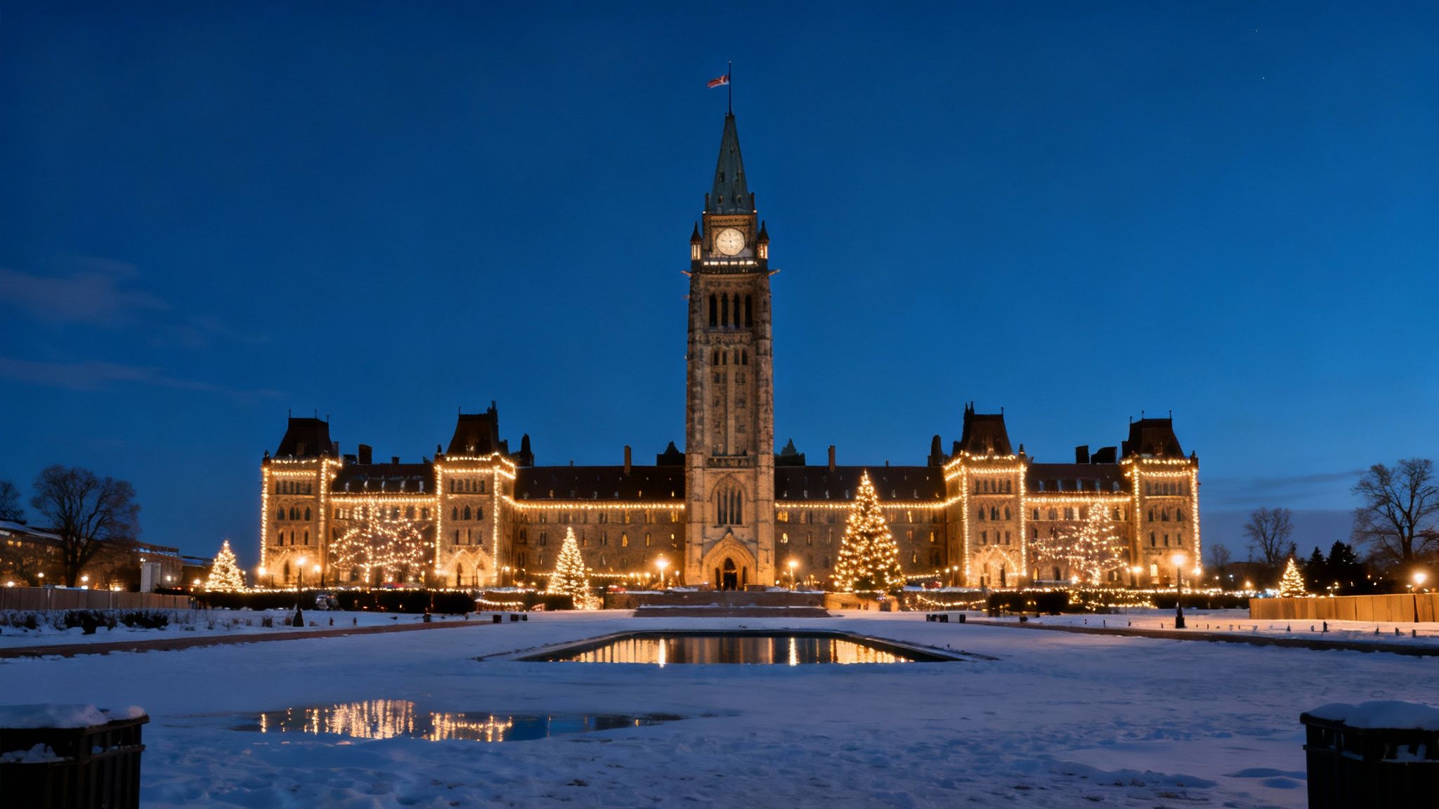 Night view of Canada's Parliament with glowing Christmas lights, snow, and reflection pond.