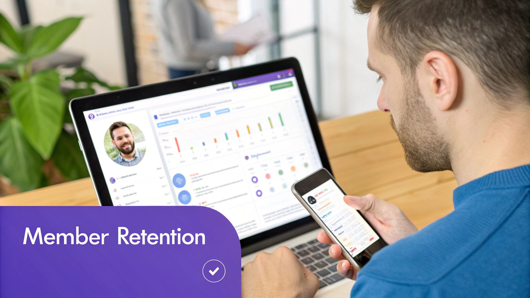 A man checks his phone while his laptop displays a 'Member Retention' dashboard.