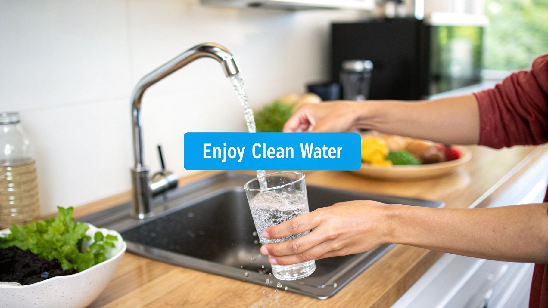 A person fills a glass with clean water from a modern kitchen faucet, next to fresh produce.