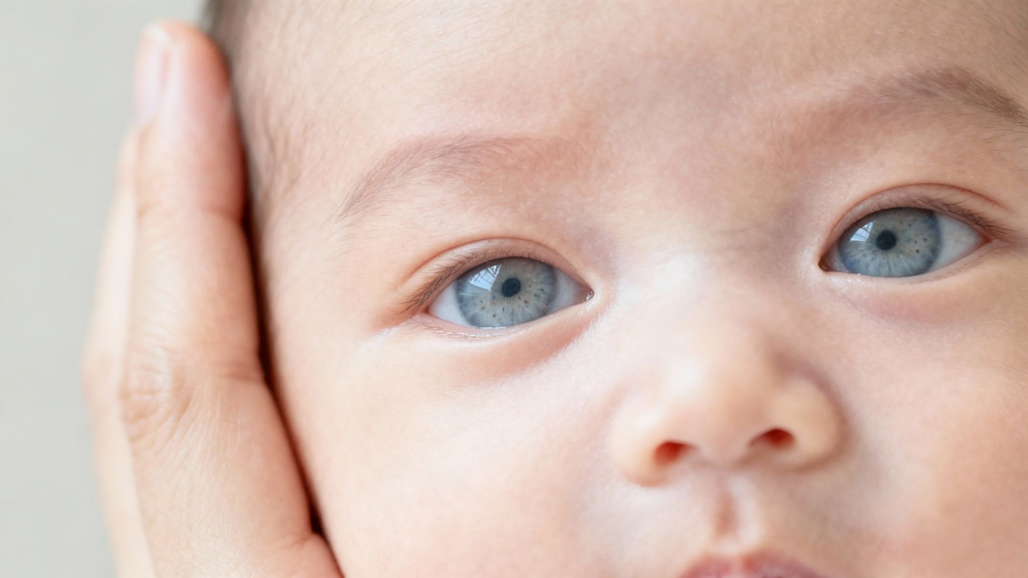 Close-up of baby with beautiful blue-grey eyes looking at camera