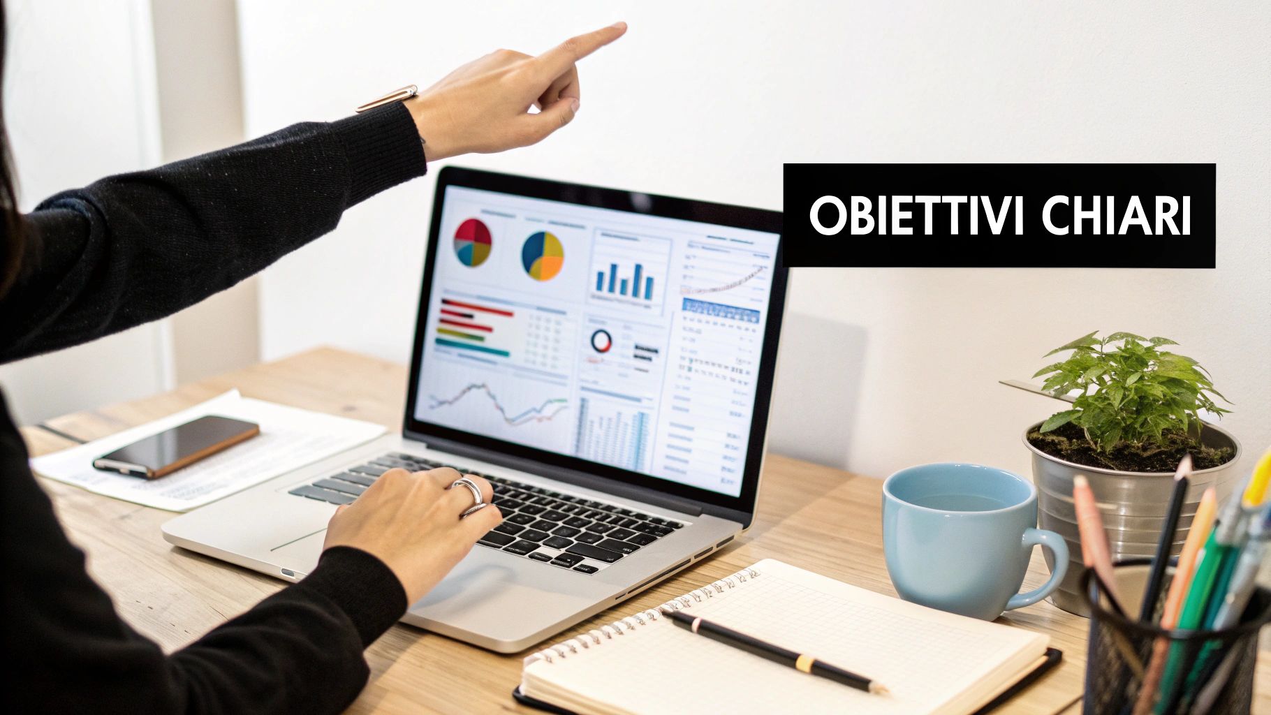 Persona che indica grafici e dati su laptop mostrando obiettivi chiari di analisi web