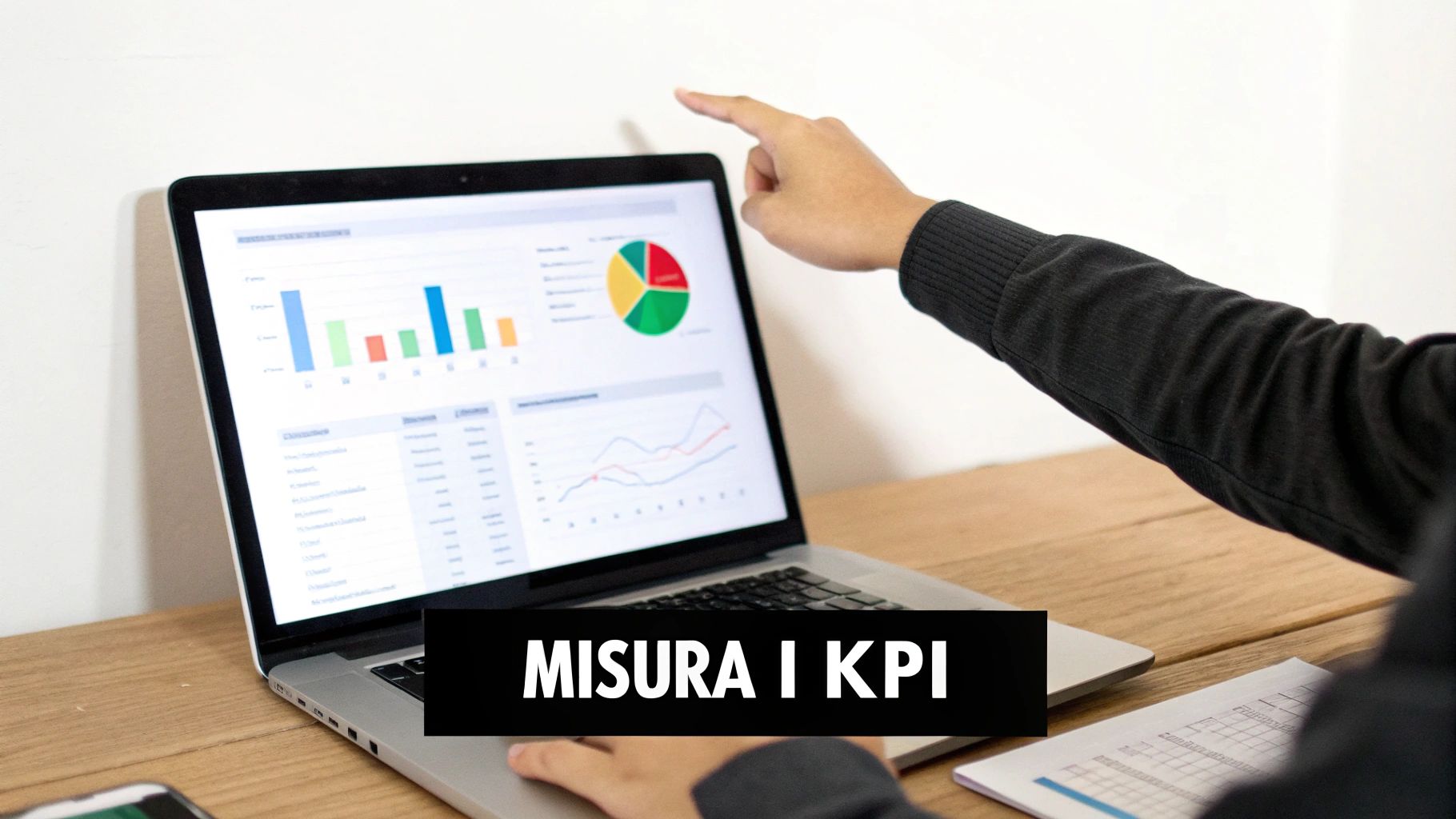 Persona che punta a un laptop con dashboard di analisi dati, mostrando grafici e il testo 'MISURA I KPI'.