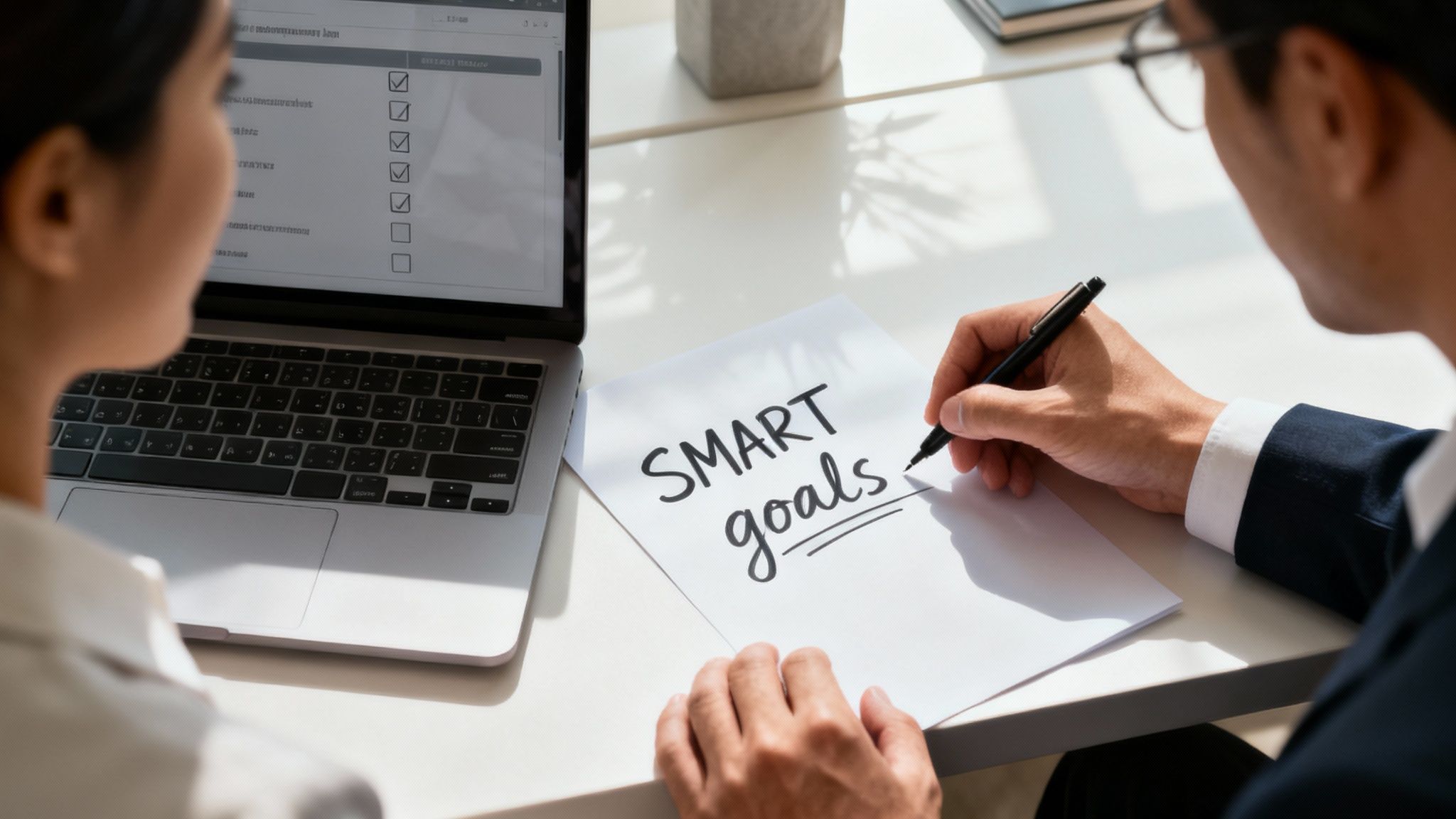 Business professionals discussing SMART goals framework with checklist on laptop during employee performance meeting