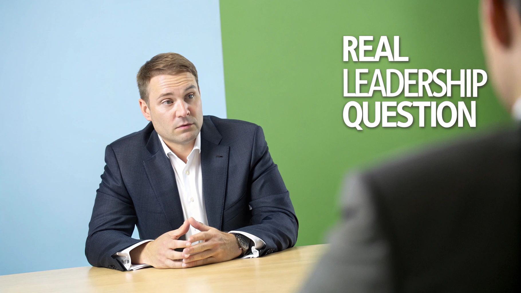 Two professional men in suits at a desk discussing a real leadership question.